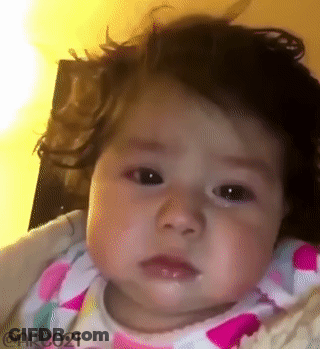 Baby Girl With Curly Hair Making Funny Face In High Chair GIF
