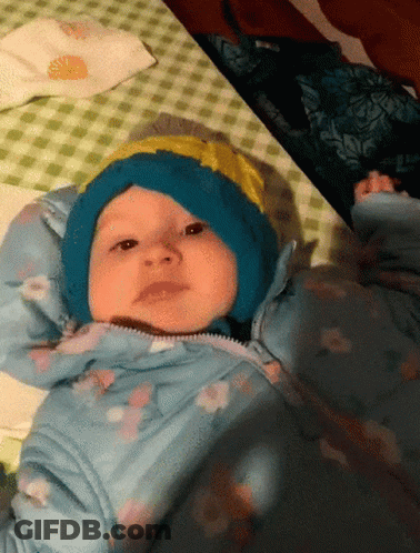 Baby In Blue Hat And Jacket Laying On Bed GIF