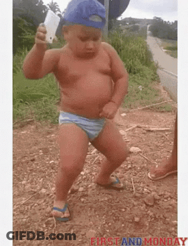 Baby In Blue Hat Dancing In Dirt Holding Cell Phone GIF
