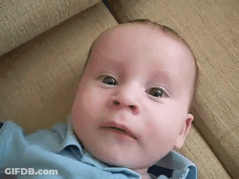 Baby In Blue Shirt On Couch Making Funny Face GIF