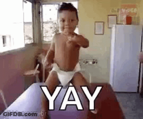 Baby In Diaper Standing On Table With Yay GIF