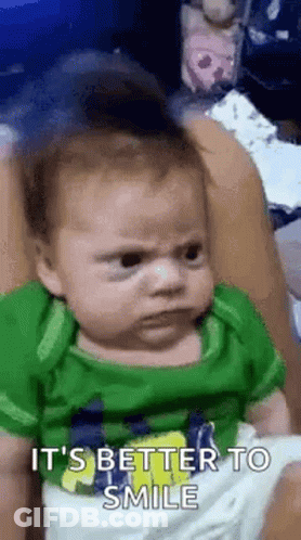 Baby In Green Shirt Making Funny Face GIF
