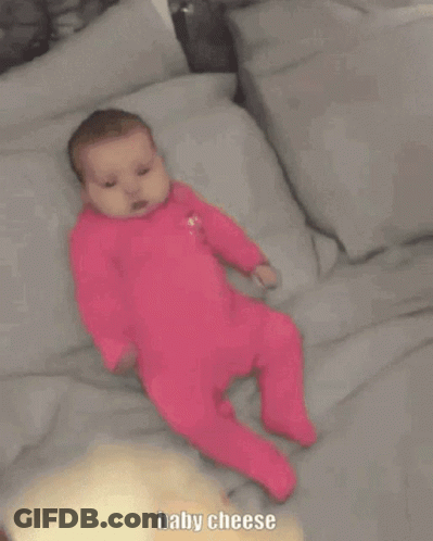 Baby In Pink Outfit Laying On Bed GIF
