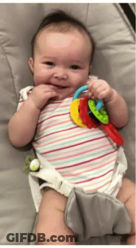 Baby In Striped Shirt Holding Rainbow Teething Toy GIF