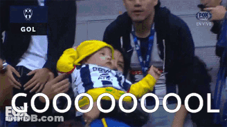 Baby In Yellow Hat Held By Man In Fox Sports Deportes Ad GIF