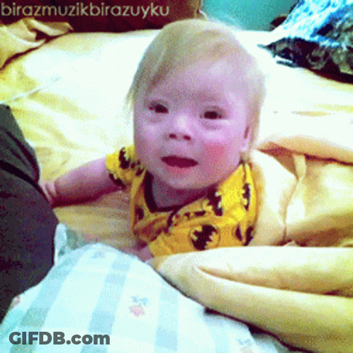 Baby In Yellow Shirt Laying On Bed GIF