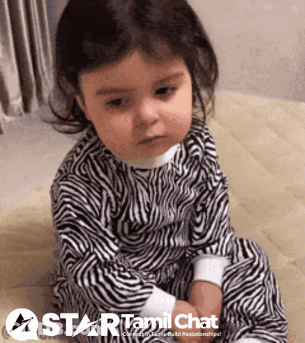 Baby In Zebra Print Pajamas Sitting On Wooden Floor GIF