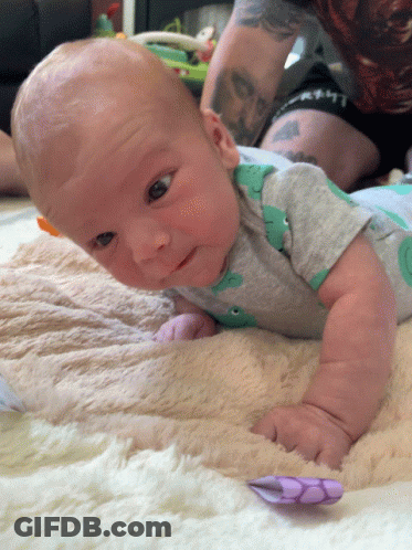 Baby Laying On Blanket In Dinosaur Shirt GIF