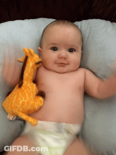 Baby Laying On Pillow With Stuffed Giraffe GIF