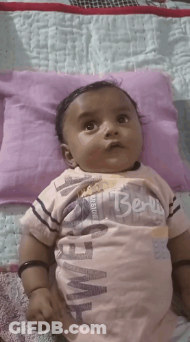 Baby Laying On Purple Pillow With Berry Shirt GIF