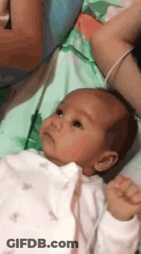 Baby Lying On Bed Held By Woman GIF