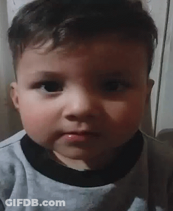 Baby Making Funny Face In Gray Shirt GIF