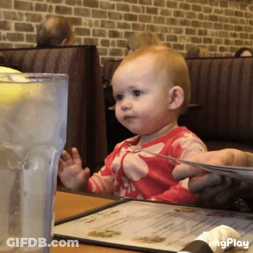 Baby Sitting At Table With Menu And Water GIF