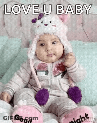 Baby Sitting In Cat Hat And Slippers On Bed GIF