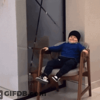 Baby Sitting In Chair Wearing Black Hat GIF