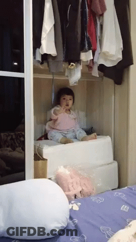Baby Sitting In Closet Next To Bed And Pillow GIF