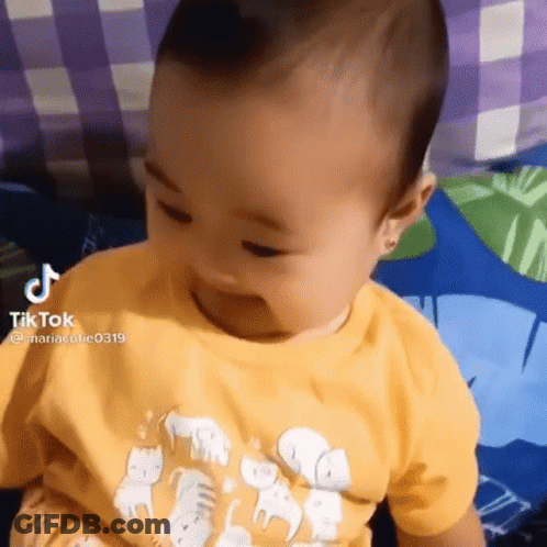 Baby Sitting On Bed In Yellow Elephant Shirt GIF