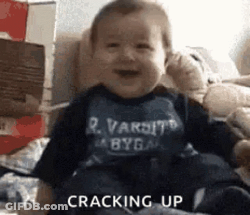 Baby Sitting On Couch Wearing Varsity Shirt GIF