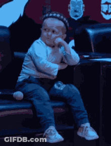 Baby Sitting On Couch With Hat GIF
