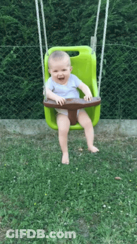 Baby Smiling On Green Swing In Grass GIF