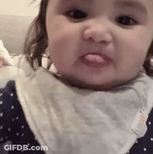Baby Sticking Tongue Out Wearing Bib GIF