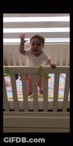 Baby Waving In White Crib GIF