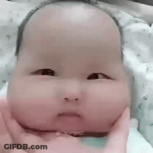 Baby With Large Head Held Making Funny Face GIF