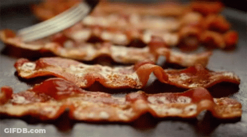Bacon Is Being Sliced On A Pan With A Fork . GIF