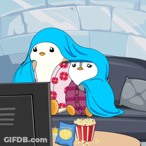 Bag Of Corn Sticks Beside Two Penguins In Blankets GIF