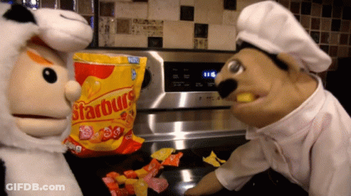 Bag Of Starburst On Counter Next To Two Puppets GIF
