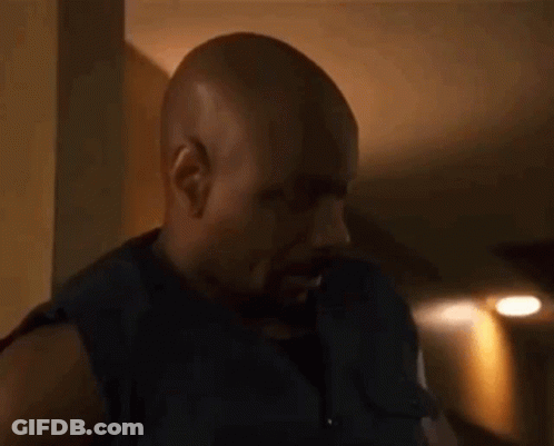 Bald Bearded Man Standing In Dark Room GIF