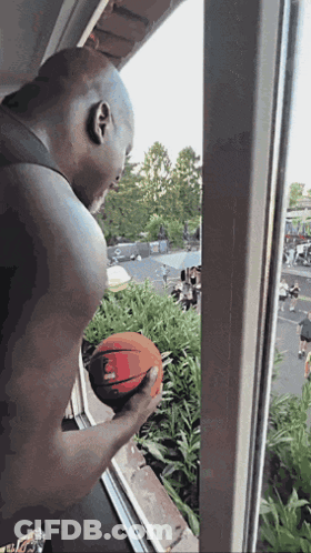 Bald Man Holding Basketball Looking Out Window GIF