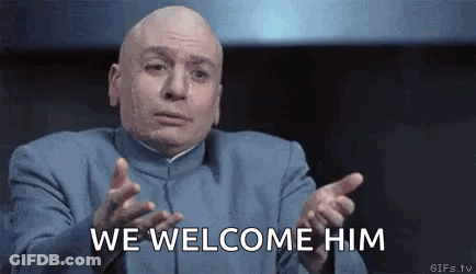 Bald Man In Blue Suit Saying We Welcome Him GIF