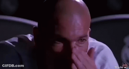 Bald Man In Dark Room Looking At Camera GIF