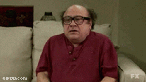 Bald Man In Glasses And Red Shirt Sitting On Couch GIF