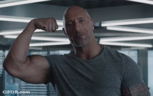 Bald Man In Gray Shirt Flexing Muscles GIF