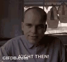 Bald Man In Gray Shirt Smiling By Window GIF
