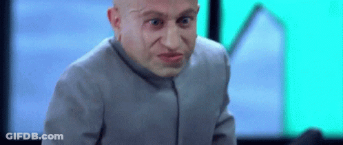 Bald Man In Gray Suit Making Funny Face Looking At Camera GIF