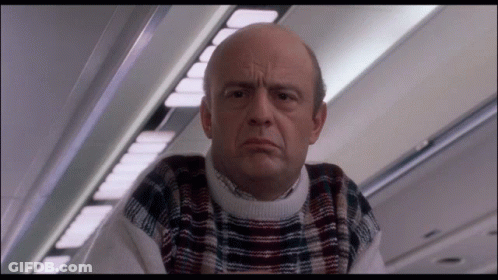 Bald Man In Plaid Sweater Looking At Camera GIF