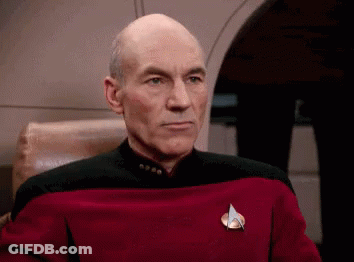 Bald Man In Red And Black Uniform Sitting In Chair GIF