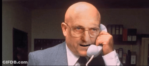Bald Man In Suit And Glasses Talking On Phone GIF