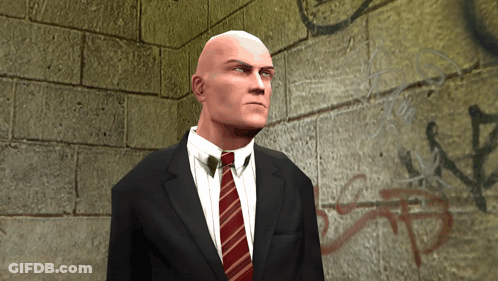 Bald Man In Suit And Tie In Front Of Brick Wall GIF