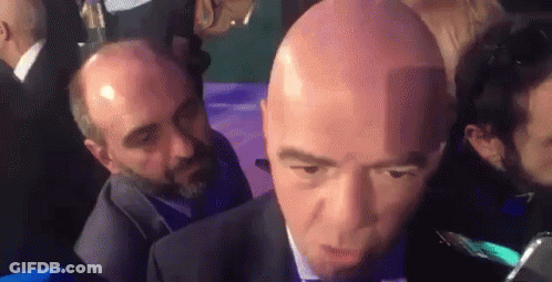 Bald Man In Suit And Tie Interviewed GIF