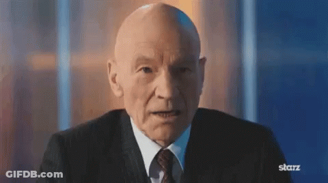 Bald Man In Suit And Tie Sitting In Front Of Starz Sign GIF