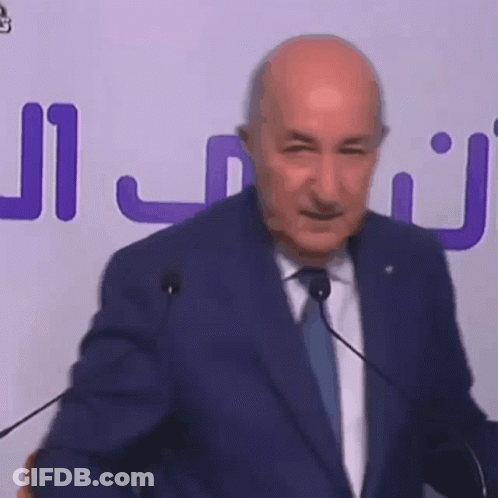 Bald Man In Suit And Tie Speaking At Microphones GIF