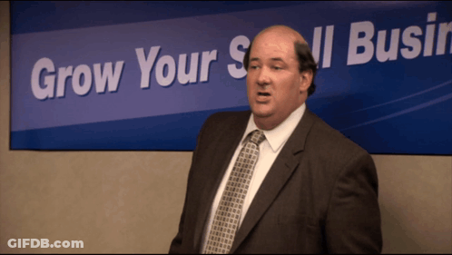 Bald Man In Suit In Front Of Grow Your Small Business Sign GIF