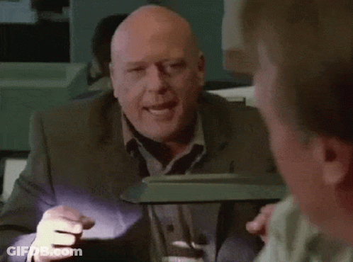 Bald Man In Suit Smiling In Front Of Lamp GIF