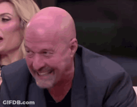 Bald Man In Suit Smiling With Woman In Background GIF