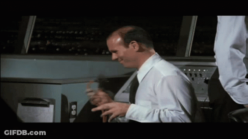 Bald Man In White Shirt And Black Tie Sitting At Machine GIF
