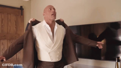 Bald Man In White Shirt And Brown Jacket Standing In Front Of TV GIF